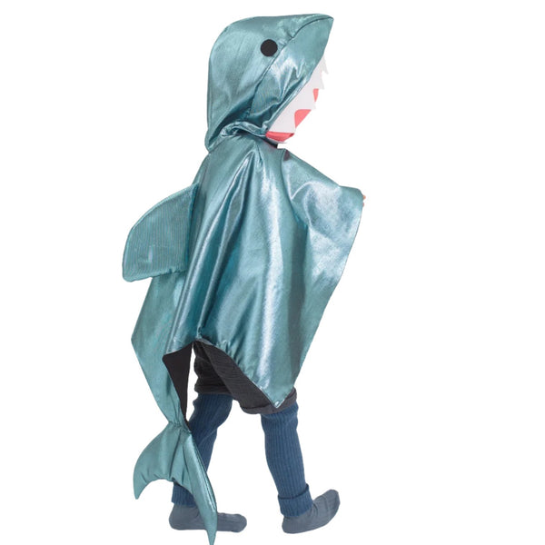 A child dressed in the Meri Meri Shark Cape Dress Up with the hood up, revealing a shark's mouth and fin, walks proudly. The playful outfit from Meri Meri makes them look like they've just emerged from the world of sea creatures.