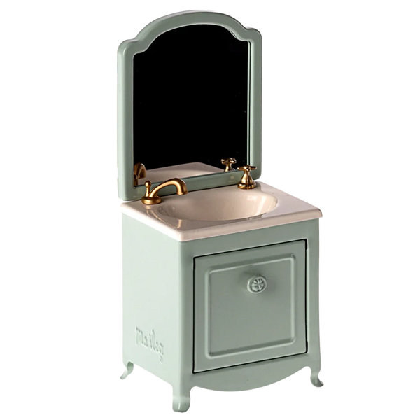 A small and elegant Maileg Sink Dresser for your mouse, featuring a mint green cabinet, a gold faucet, an attached mirror, and a cleverly hidden small closet under the sink.