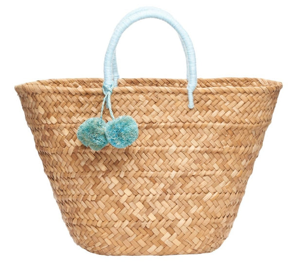 Kayu St. Tropez Pom Pom Straw Tote with light blue pom-pom accessory on handle, isolated on a white background.