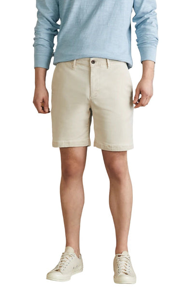 A person wearing a light blue long-sleeve shirt, Faherty Coastline Chino Short from Faherty, and white sneakers is standing against a plain white background.