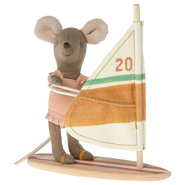 The Mail Beach Mice, Surfer Little Sister by Maileg is a charming stuffed toy mouse dressed in a pink outfit and standing on a wooden surfboard with a sail marked "20." Featuring magnetic hands, this delightful toy is perfect for children aged 3 and up.