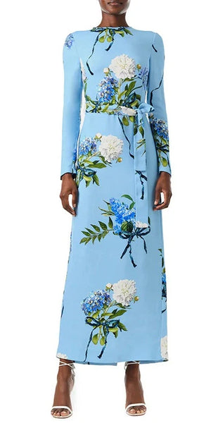 Person wearing a Monique Lhuillier Printed Crepe Long Sleeve Sheath Dress, paired with white heeled sandals.