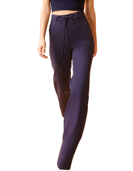 Person wearing Ulla Johnson Daya Pant, midnight blue high-waisted pants with a drawstring waistband, and a cropped black top, walking.