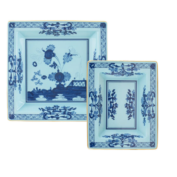 Two porcelain trays from the GINORI 1735 Oriente Italiano Iris Tray Collection by Ginori 1735, featuring iris blue hues with blue carnation floral motifs and geometric patterns, one larger and one smaller, stacked offset in the traditional Antico Doccia shape.