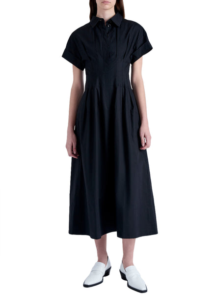 Person wearing a black, short-sleeved, collared Proenza Schouler Balston Dress with button details, paired with white loafers.