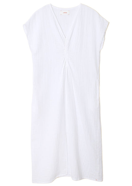 A white, short-sleeved midi V-neck dress with gathered detail at the center. The fabric appears lightweight and slightly textured, featuring convenient side seam pockets. This is the Xirena Drue Dress from Xirena.