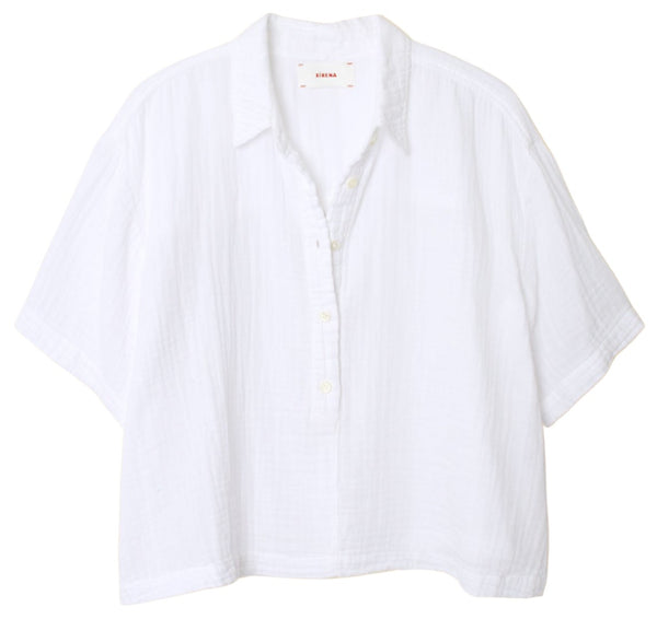 The Xirena Ansel Top by Xirena is a white, short-sleeved, button-up shirt with a collar and a relaxed fit. Crafted from lightweight cotton poplin, made in Los Angeles, it features a lightly textured fabric and includes a tag inside the collar.