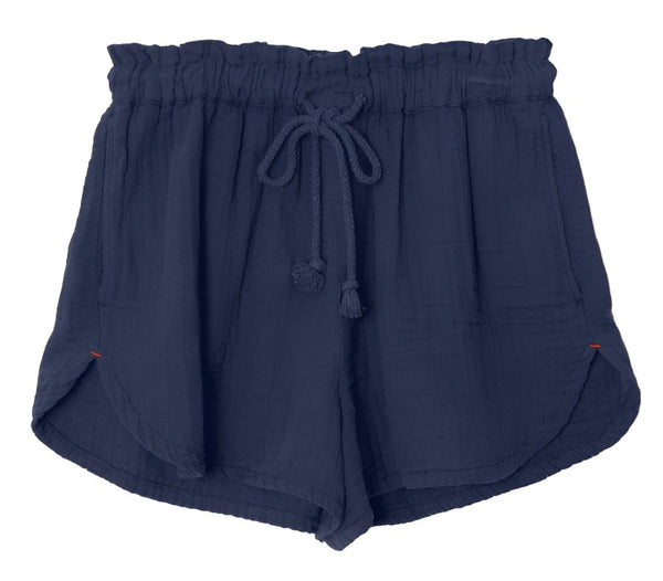 A pair of Xirena Starla Shorts by Xirena in dark blue, high-waisted dolphin style made from cotton gauze, featuring an elasticized drawstring waistband and side pockets.