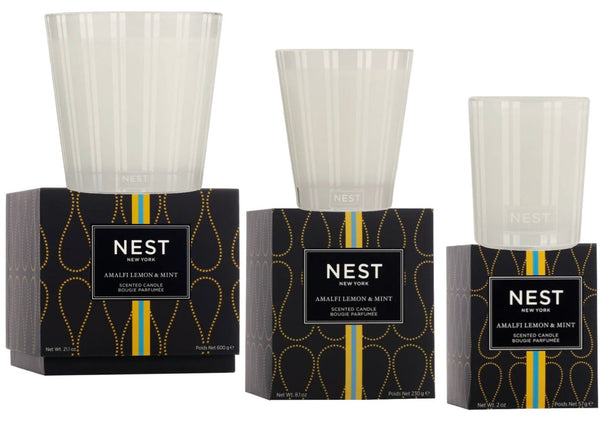 Three candles from the NEST Amalfi Lemon & Mint Collection by Nest are displayed in varying sizes, each featuring sleek black and gold packaging with a clear glass holder on top, evoking the fresh, invigorating scents of Italy’s Amalfi Coast.