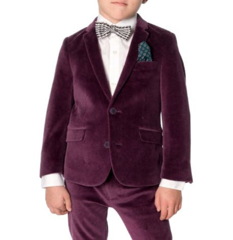 A child wearing an Appaman Boys' Velvet Blazer with a crisp white dress shirt, patterned bow tie, and green pocket square stands facing forward, ready for holiday parties.