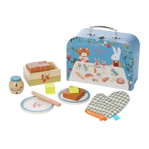 The Manhattan Toys Forest Tales Baking Set by Manhattan Toy is a delightful wooden play kitchen accessory for children. It includes a toy oven mitt, honey jar, butter, rolling pin, and baking tools with plates. Displayed in front of a decorated blue suitcase adorned with animal illustrations, it makes the perfect toddler birthday gift.