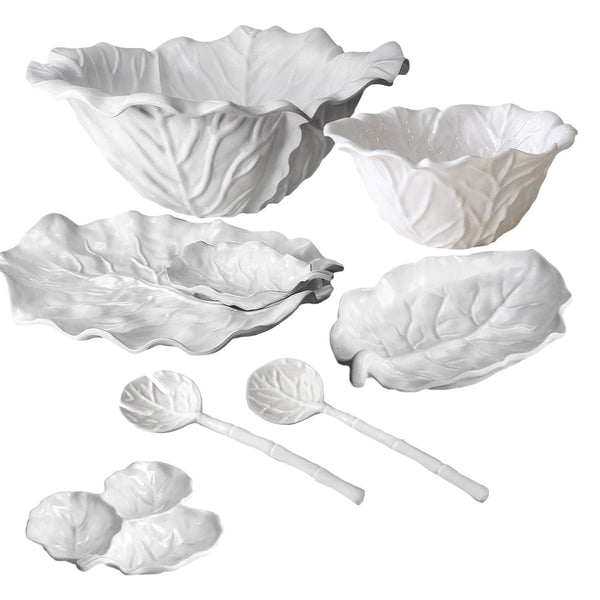 Explore the Beatriz Ball Vida Lettuce Serving Collection: a selection of white ceramic dishes and bowls elegantly crafted to resemble cabbage leaves, including a large bowl, small bowls, plates, and spoons. Beautifully presented against a white background, this collection embodies the sophisticated design of Beatriz Ball.