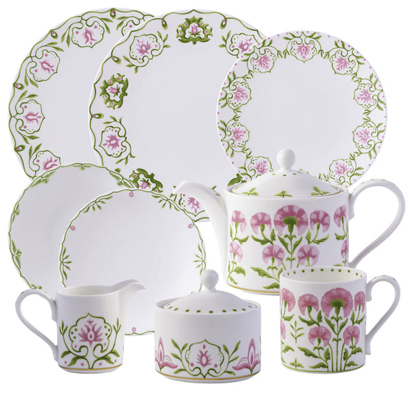 The Royal Crown Derby Cobblers Cove Camelot Collection offers a stunning set of white porcelain dinnerware featuring delicate pink floral and green leaf patterns. This beautiful collection includes plates, a teapot, a creamer, a sugar bowl, and two mugs—perfectly suited for an exquisite fine bone china experience reminiscent of a luxury boutique hotel.