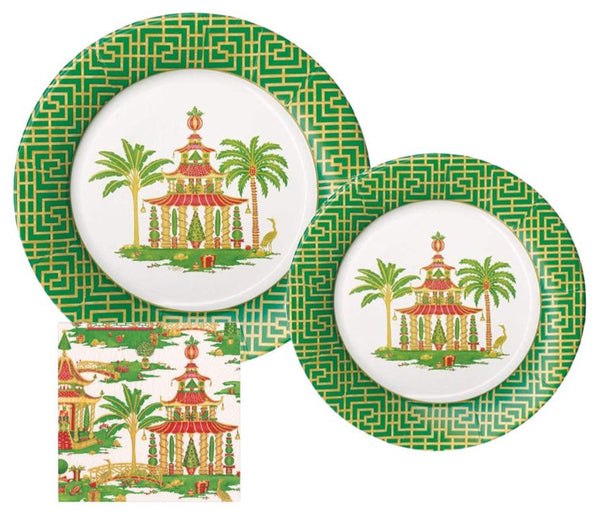 The Caspari Christmas Pagodas Collection from Caspari includes two decorative dinner plates and a cocktail napkin that showcase a pagoda design with palm trees and green geometric borders.