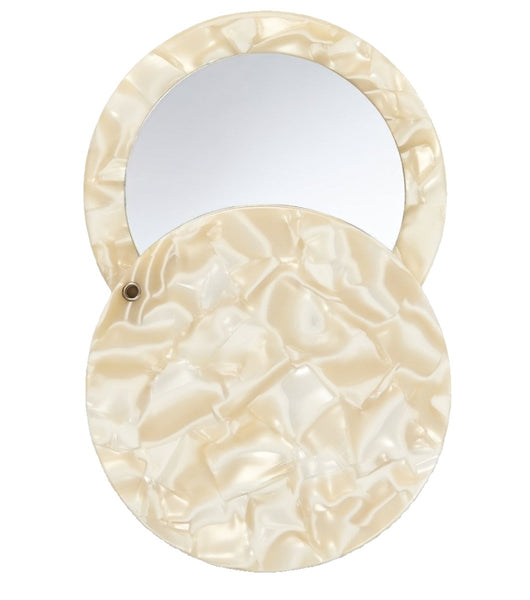 Machete Circle Mirror with a beige, textured exterior made from handmade Italian acetate; one side is a mirror, and it features a swivel opening.