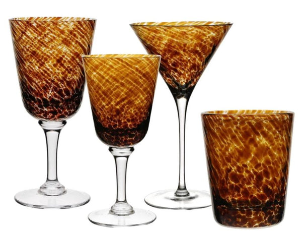 Four drinking vessels with a brown and amber tortoise pattern, including two wine glasses, one martini glass, and one tumbler, showcase the elegance of colored glass. From the William Yeoward Crystal Vanessa Tortoise Collection, these pieces may require a Proposition 65 warning.