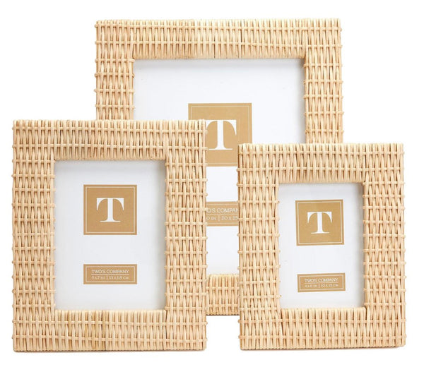 Three distinct-sized frames from the Two's Company Criss Cross Weave Frame Collection are arranged in a staggered formation against a white backdrop. Each frame, designed by Two's Company, boasts a natural rattan Criss Cross weave and includes a placeholder card adorned with a gold "T" logo in the center. These frames are perfect for adding charm to your tabletop display.