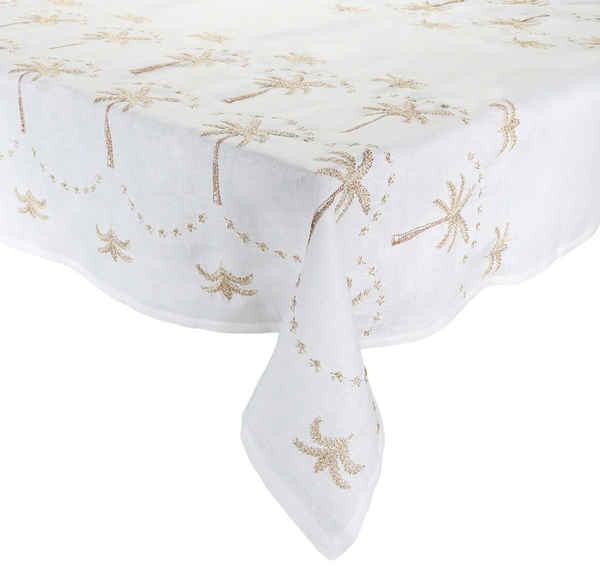 Kim Seybert Embroidered Palm Tablecloth with a golden starfish and seashell embroidery design, draped over a table with one corner hanging down.