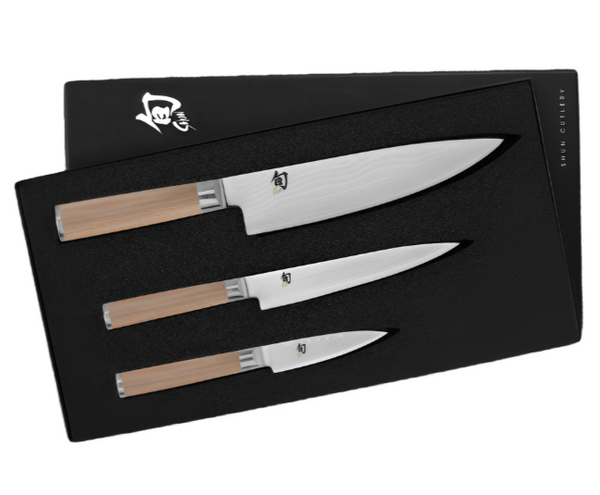 The Shun Classic Blonde Starter Knife Set by Shun includes three knives with light wooden handles, featuring a Chef's Knife with a VG-MAX cutting core, all elegantly displayed in a sleek black box.