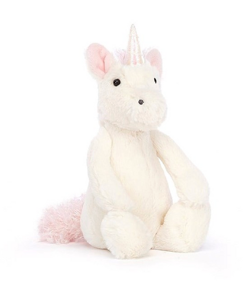 The Jellycat Bashful Unicorn, Little, with vanilla fur, pale pink ears, a pink tail, and a small holographic horn, sits upright against a white background.