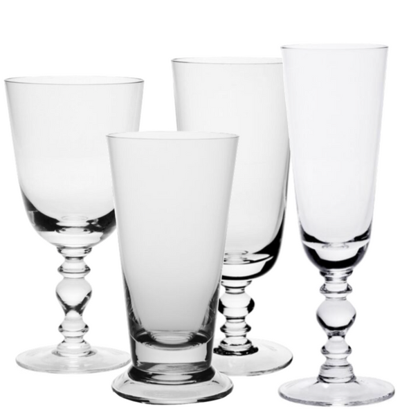 Four items from the William Yeoward Crystal Fanny Clear Collection by William Yeoward Crystal, featuring distinct designs: two large wine goblets, a tall tumbler, and a champagne flute on a white background.