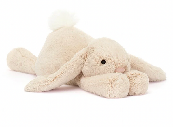 Jellycat Smudge Rabbit, Big with floppy ears, oatmeal fur, a small pink nose, and a white fluffy tail lying down on its belly—a loving companion for any sleepy sweetie.