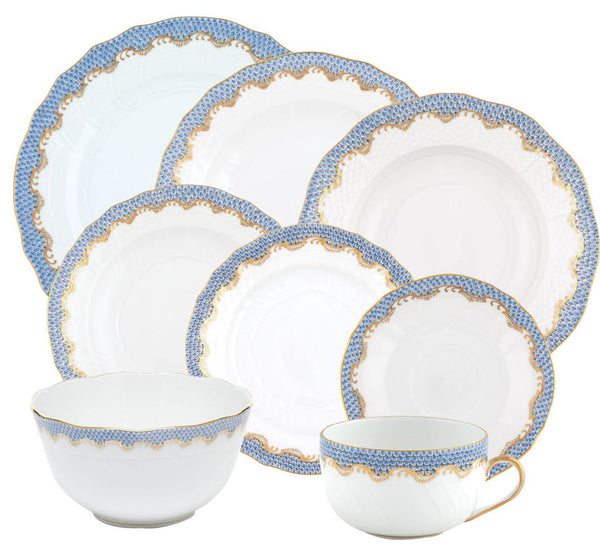 A set from the Herend Fish Scale Light Blue Collection by Herend, featuring various plates, a bowl, and a teacup adorned with intricate blue and gold scallop edge designs that invite artistic appreciation.