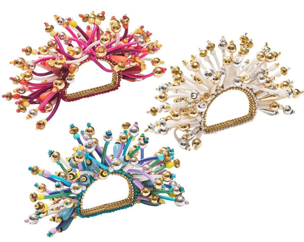 Three vibrant and spiky Kim Seybert Fun Burst Napkin Rings embellished with metallic silver and gold beads, available in pink, white, and blue accents.