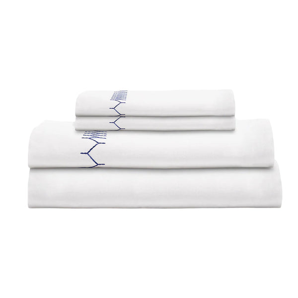 A neatly folded stack of white percale sheets with blue hand embroidery detailing, made from organic cotton, is featured in the John Robshaw Stitched Indigo Bedding Collection - Final Sale by John Robshaw.