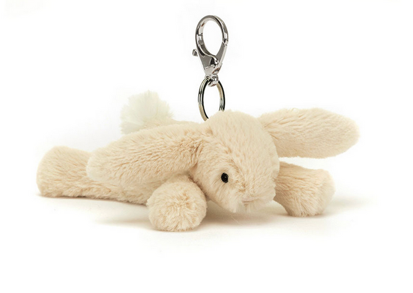 A plush bunny keychain with soothing beige fur, floppy ears, and a metal clasp. Complete with a Jellycat tag, this Jellycat Smudge Rabbit Bag Charm is perfect for hanging on your favorite bag or keyring.