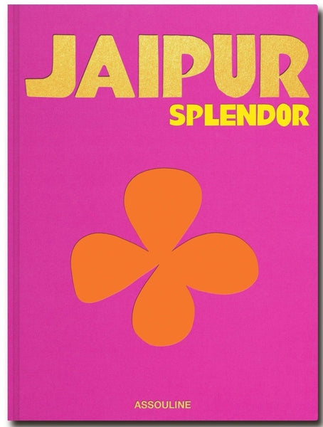 Bright pink book cover with "Jaipur Splendor" in large gold text, "Assouline" in smaller yellow text, and an orange clover-like symbol centered below the text, reminiscent of the Pink City’s Hawa Mahal. The book is published by Assouline.