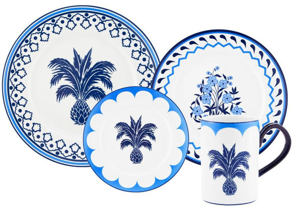 A collection of blue and white porcelain dishes and a mug from the Aquazzura Jaipur Blue Collection by Aquazzura Casa, adorned with hand-painted designs of a pineapple tree and flowers showcasing intricate handcrafted details.