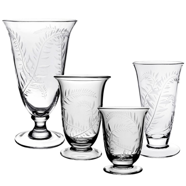 Four vases from the William Yeoward Crystal Jasmine Flower Vase Collection, each crafted from clear glass in different heights and intricately etched with a delicate jasmine vine motif, shown against a white background.