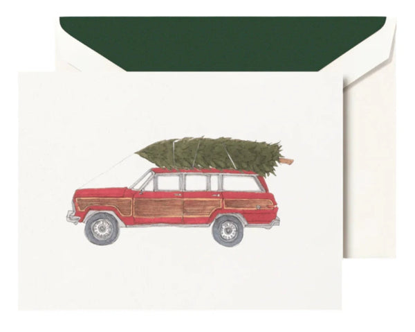 Illustration of a red station wagon that evokes the classic look of a vintage Jeep, complete with a Christmas tree secured on top, featured on the Crane Jeep with Tree Card Set which includes a greeting card paired with a green envelope by Crane.