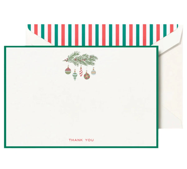 The Crane Bordered Ornaments Thank You Card Set by Crane showcases a straightforward design featuring bordered ornaments and a pine branch illustration, highlighted by a prominent red "Thank You" text at the bottom. The accompanying envelope includes a festive liner with red, green, and white stripes.