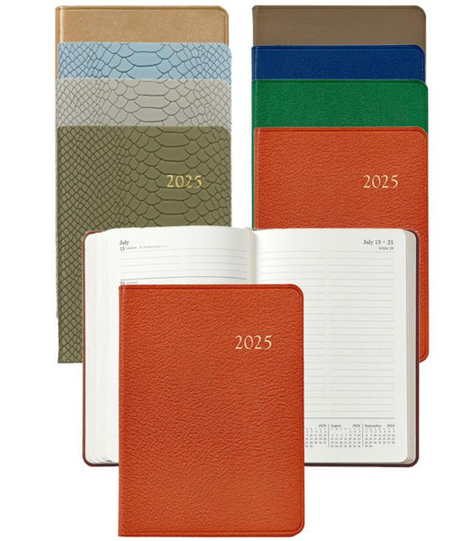 Assorted Graphic Image 2025 Weekly Calendars with various cover designs are displayed. Two open notebook planners reveal detailed appointment pages, while four others are closed, showcasing diverse cover colors and textures crafted from acid-free paper.