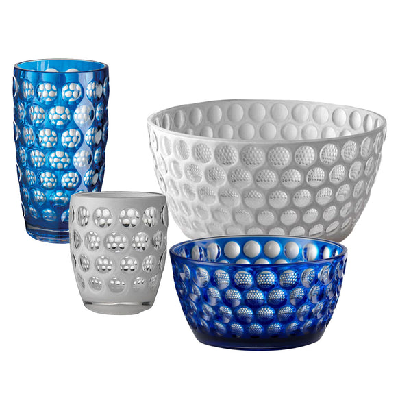 The Lente Acrylic Collection by Mario Luca Giusti offers four stunning glass-like items with a honeycomb pattern, perfect for outdoor entertaining: a tall blue tumbler, a small white tumbler, a large white bowl, and a small blue bowl. To maintain their vibrant colors and exquisite design, hand washing is recommended.