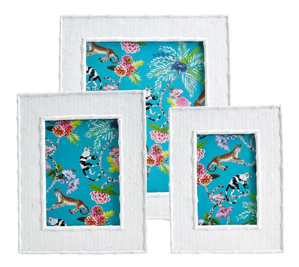 Three white photo frames from the Two's Company Liana Photo Frames Collection showcase intricate patterns, each holding a blue background adorned with tropical designs of leopards and floral elements. Perfect for adding a vibrant touch to your summer home decor.