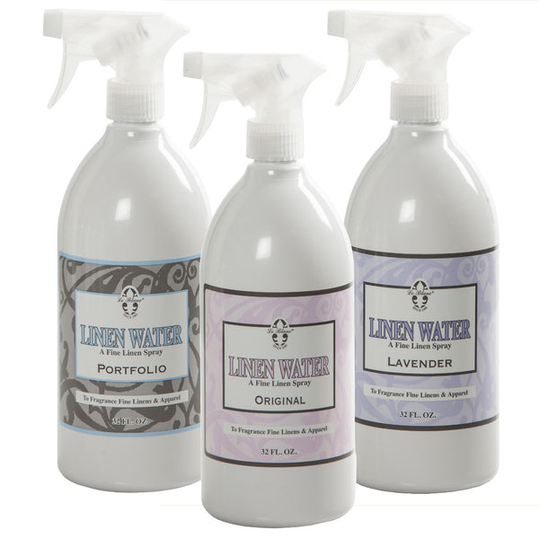 Three 32 fl. oz. bottles of Le Blanc Linen Water are shown, labeled as "Portfolio," "Original," and "Lavender" by Le Blanc, each crafted to freshen linens and apparel with a delightful fragrance.