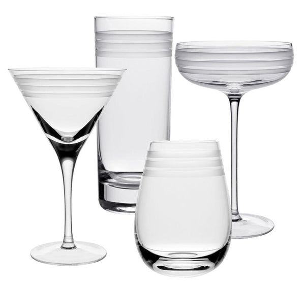 Part of the William Yeoward Crystal Madison Collection, these four assorted clear glass drinkware items from William Yeoward Crystal include a martini glass, a highball glass, a coupe glass, and a stemless wine glass, each featuring copper-wheel engraved horizontal lines near the rims.