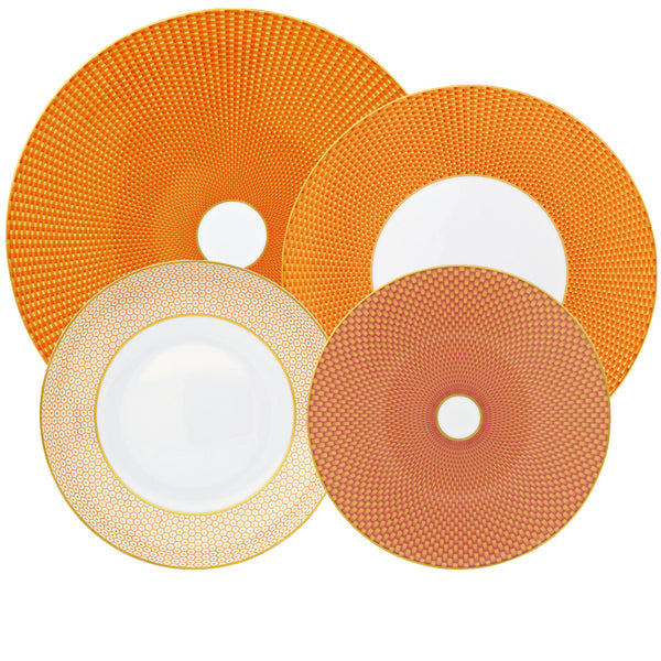 Set of four round plates from the Raynaud Tresor Orange Collection, showcasing intricate orange and yellow geometric patterns with both solid and white centers. These hand-painted Raynaud plates epitomize poetic porcelain artistry.