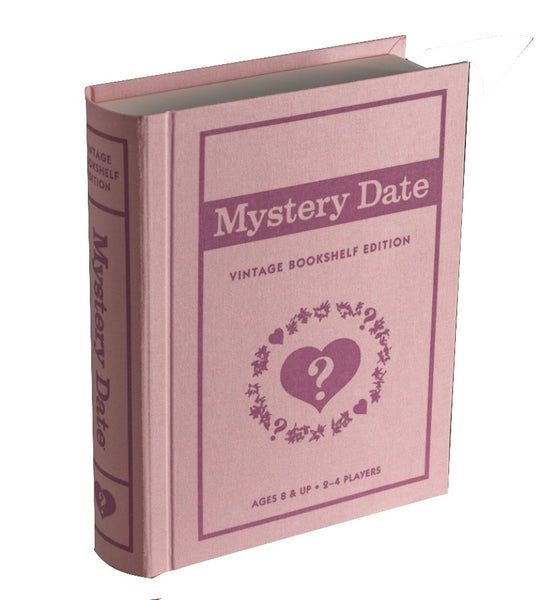 A pink "Mystery Date Vintage Bookshelf Edition" game by WS Game Company, suitable for ages 8 and up and designed for 2-4 players, sits charmingly alongside a fabric-wrapped book and a Vintage Monopoly game complete with die-cast tokens.