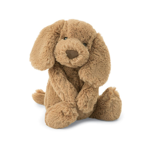 A Jellycat Bashful Toffee Puppy, Medium with long floppy ears and a dark brown nose is sitting with its front legs folded.