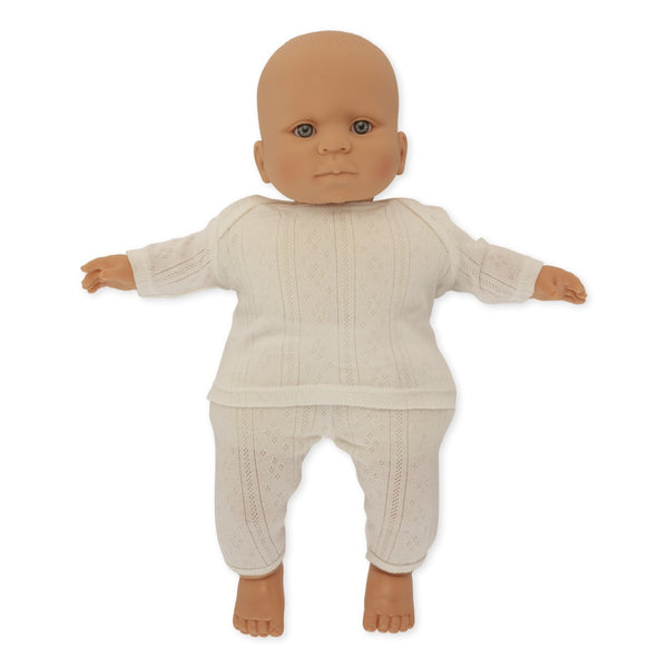 Konges Slojd Alfie the Doll from Konges Slojd is a baby doll with a bald head, dressed in an organic cotton white long-sleeve top and matching pants. The doll features a neutral facial expression and is depicted lying with its arms and legs slightly spread. It is crafted to meet European safety standards.