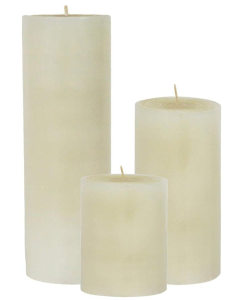 Three candles from the Perin-Mowen Solid Pillar Candle Collection by Perin Mowen, each with different heights, stand upright against a white background.