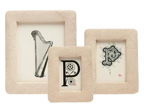 Three beige photo frames from the Pigeon and Poodle Ancona Frame Collection by Pigeon & Poodle, featuring illustrations of a harp, a decorative letter "P," and an ornate letter "P," are arranged in a row against a white background, evoking cherished memories.