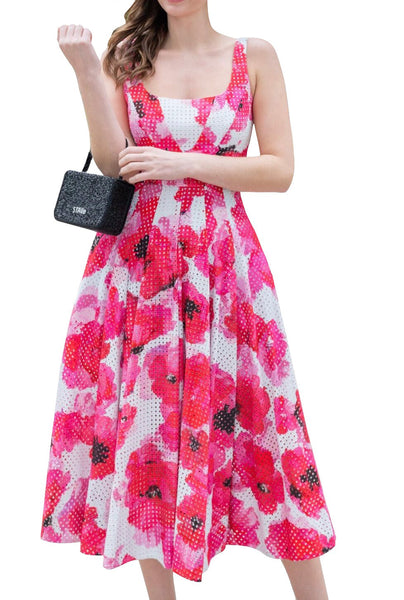 A woman in a sleeveless pink and white floral, cotton eyelet midi length Prabal Gurung dress carrying a black handbag.