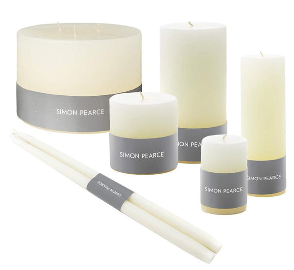 The Simon Pearce Ivory Candle Collection, featuring various sizes of ivory candles with gray bands, adds a touch of elegance to your home decor. These artisan candles exemplify the beauty of small-batch craftsmanship.