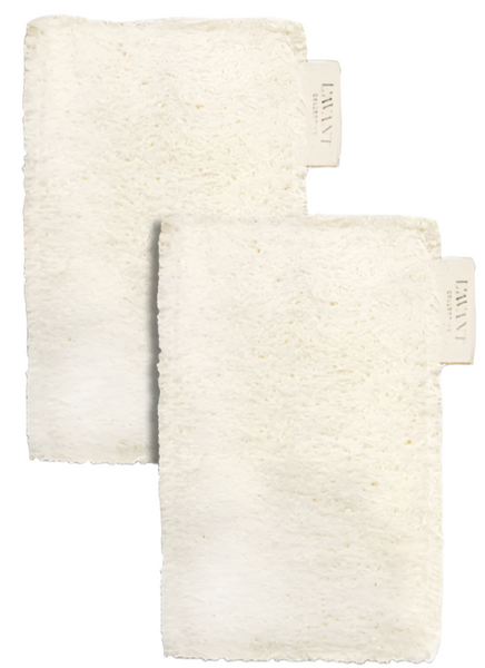 Two white, fluffy, rectangular washcloths are positioned vertically with one slightly in front of the other. They each have a beige tag with text attached to one corner, reminiscent of L'Avant Collective's L'Avant Eco Friendly Sponges, Set of 2 that add a touch of sustainability to your daily routine.