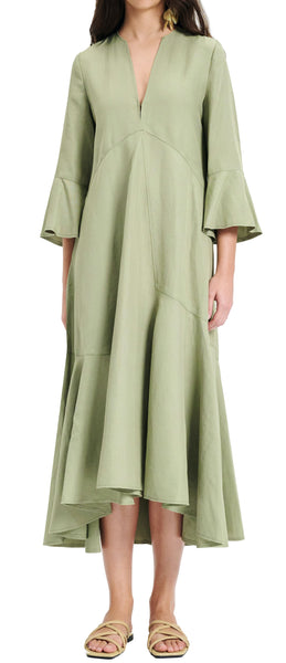 A person wearing a long-sleeved, olive green, V-neck Dorothee Schumacher Summer Cruise Maxi Dress with asymmetrical hemline and ruffled cuffs by Dorothee Schumacher. The linen blend dress features beige sandals, enhancing the overall look.